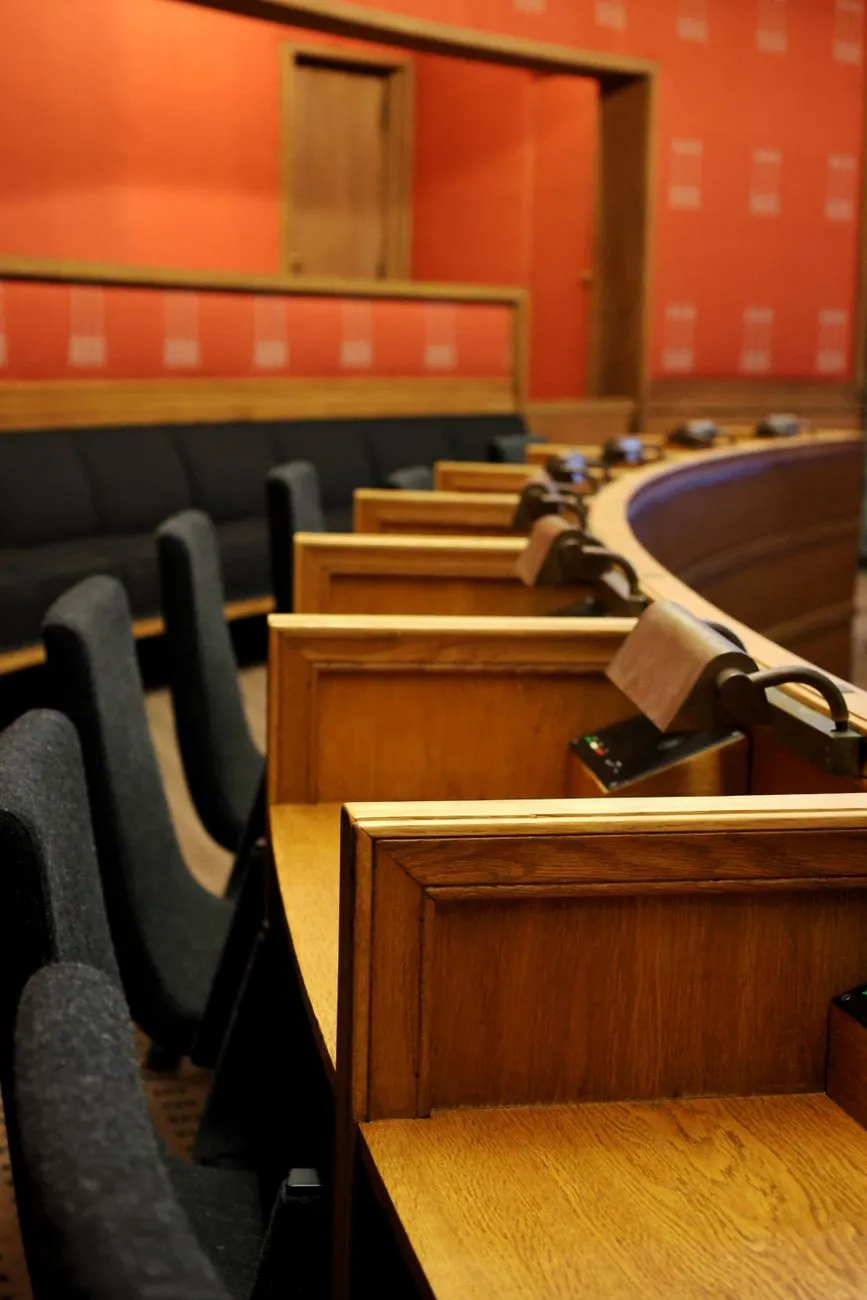 Sitzplätze im Parlamentssaal mit Holztäfelung und roten Wänden
