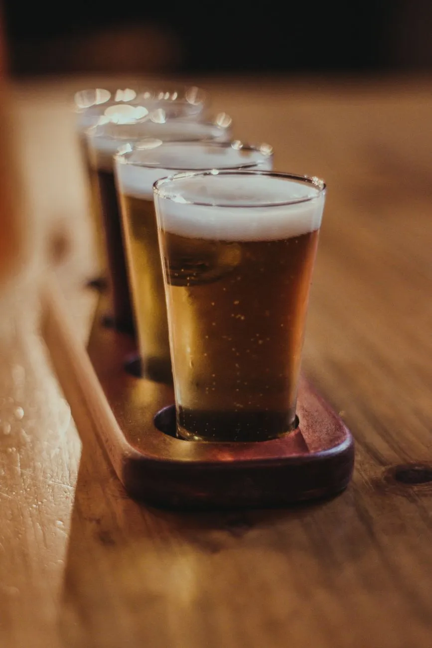 Bierverkostung: Vier Gläser Bier in einem Holztablett auf Holztisch
