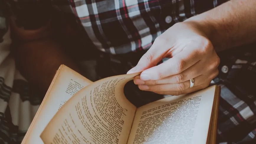 Buch lesen: Eine Hand blättert durch die Seiten eines alten Buches.