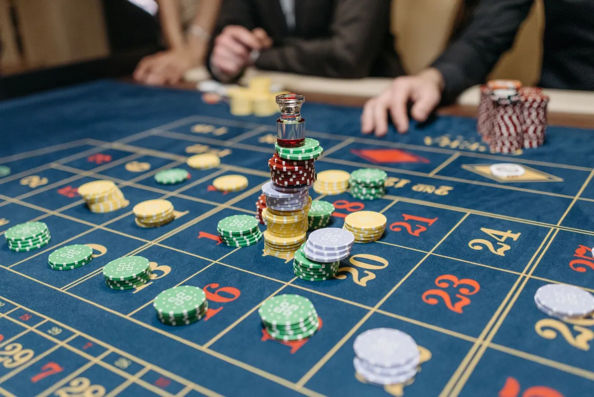 Roulette-Tisch mit Jetons und Spielern im Hintergrund in einem Casino